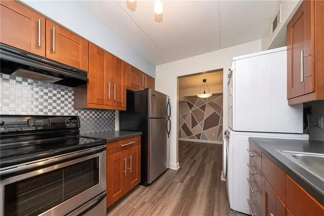 a kitchen with stainless steel appliances granite countertop a refrigerator and wooden cabinets