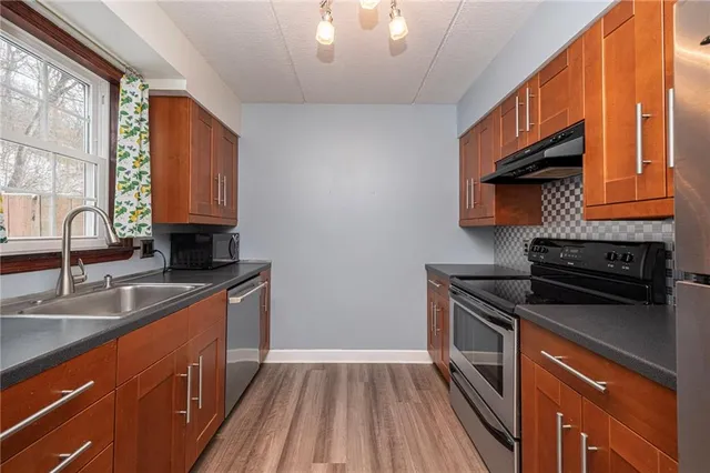 a kitchen that has a sink wooden floor and a stove