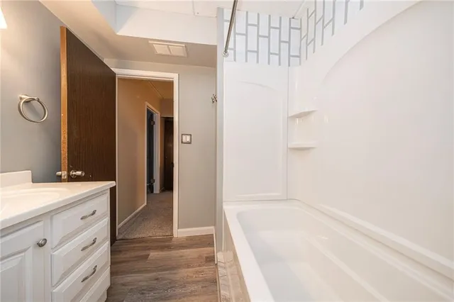a bathroom with a bathtub sink vanity and mirror