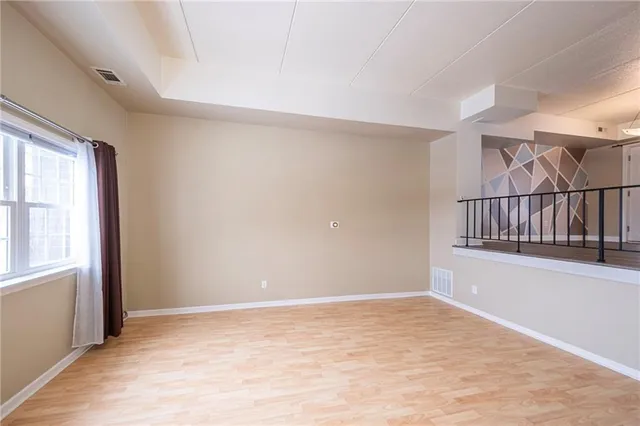 a view of an empty room with wooden floor and windows