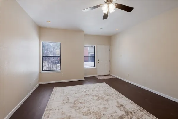 an empty room with chandelier fan and windows