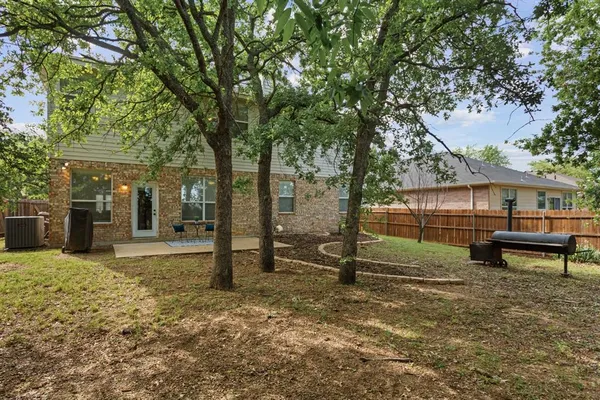 a backyard of a house with large trees and brick walls