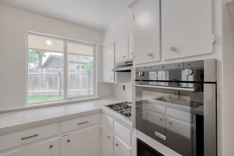 a kitchen with white cabinets and appliances