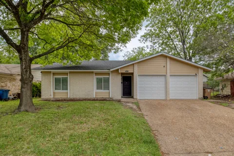 front view of house with a yard and large trees