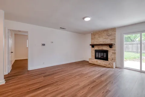 an empty room with wooden floor fireplace and windows