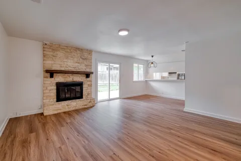 a view of empty room with wooden floor and fireplace