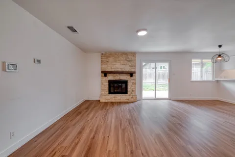 an empty room with wooden floor fireplace and windows
