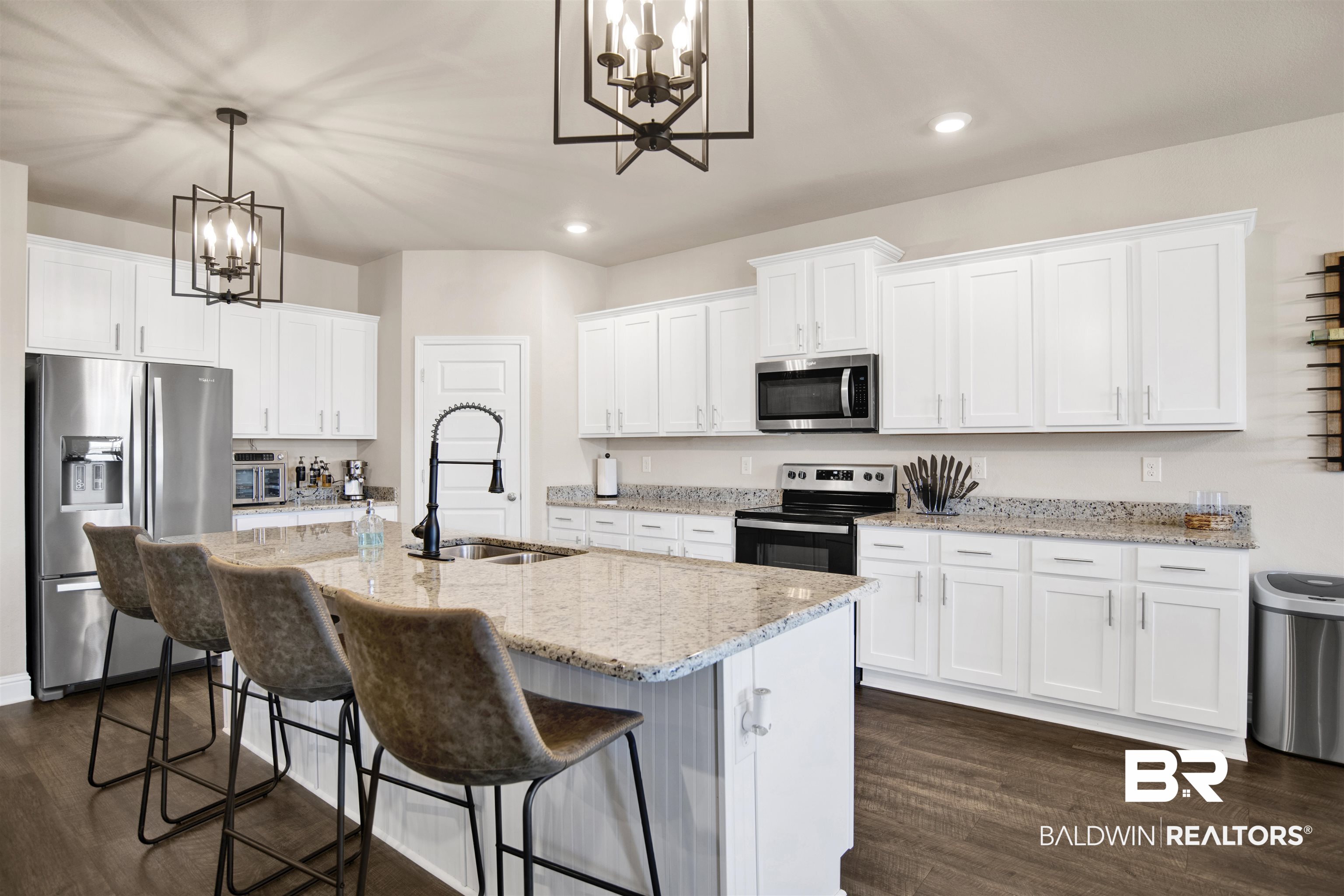 8493 Bronze Lane Foley, AL 36535 - Photo 12 of 38 Kitchen featuring a large island with a stone countertop, white shaker cabinetry, stainless steel appliances, and dark wood-finish flooring