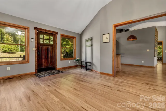 a view of an empty room with wooden floor fireplace and a window