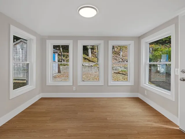 a view of an empty room with a window and wooden floor