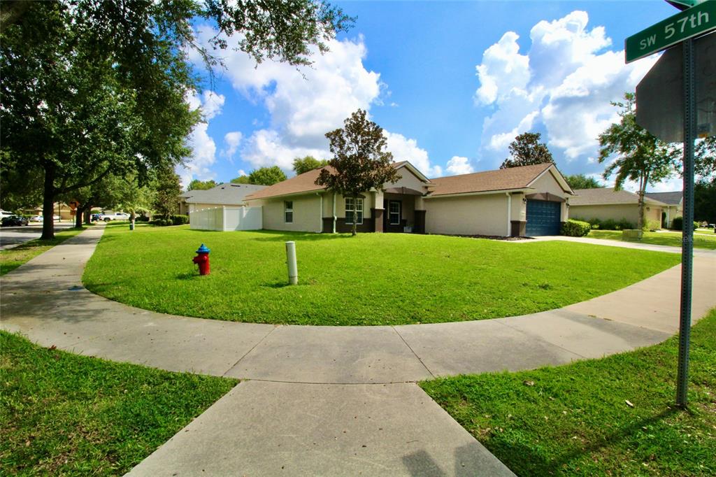 5739 Southwest 40th Street Ocala, FL 34474 - Photo 4 of 52 a view of a white house with a big yard plants and large trees