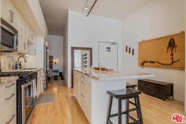 a kitchen with stainless steel appliances granite countertop a stove top oven a sink dishwasher a dining table and chairs with wooden floor