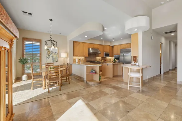 a kitchen with stainless steel appliances kitchen island granite top table and chairs