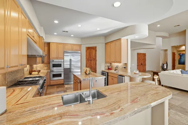 a large kitchen with stainless steel appliances kitchen island granite countertop a large kitchen island a stove and a sink