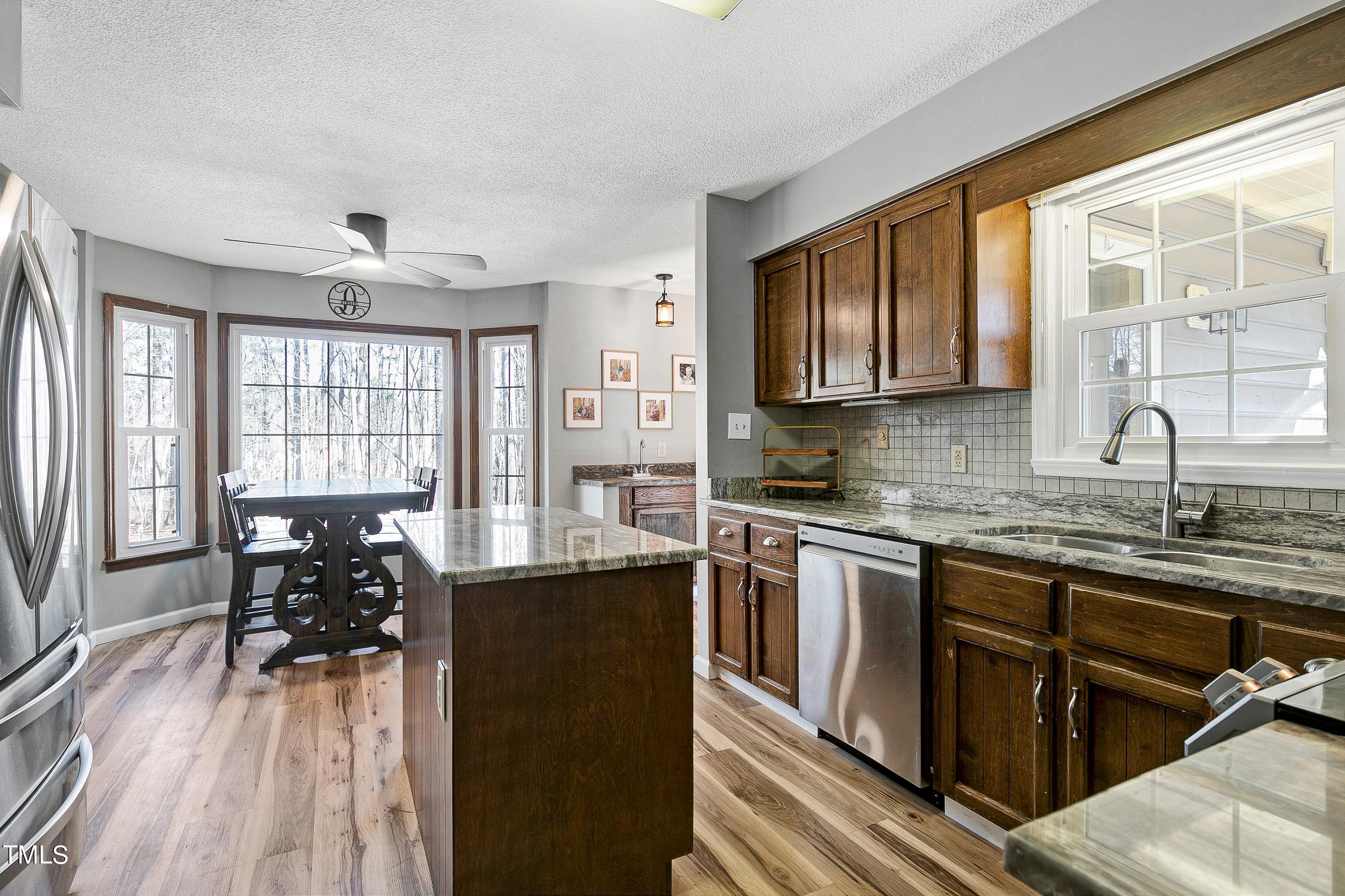 10021 Sycamore Road Raleigh, NC 27613 - Photo 13 of 40 a kitchen with stainless steel appliances granite countertop a stove top oven a sink dishwasher a dining table and chairs with wooden floor