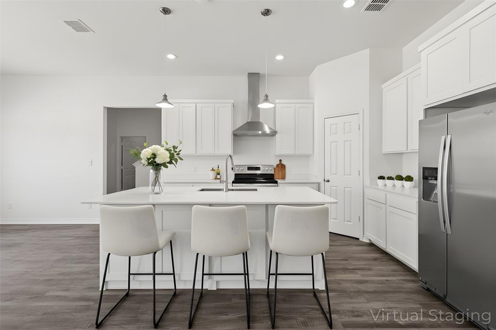 a kitchen with stainless steel appliances a dining table chairs and wooden floor