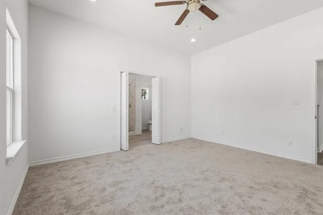 an empty room with a ceiling fan and carpet