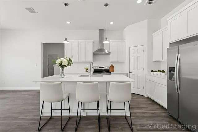 a kitchen with stainless steel appliances a dining table chairs and wooden floor
