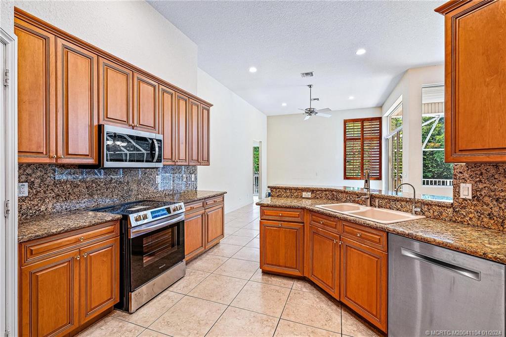 105 Henry Sewall Way Stuart, FL 34996 - Photo 14 of 33 a kitchen with stainless steel appliances granite countertop wooden cabinets a sink and a stove