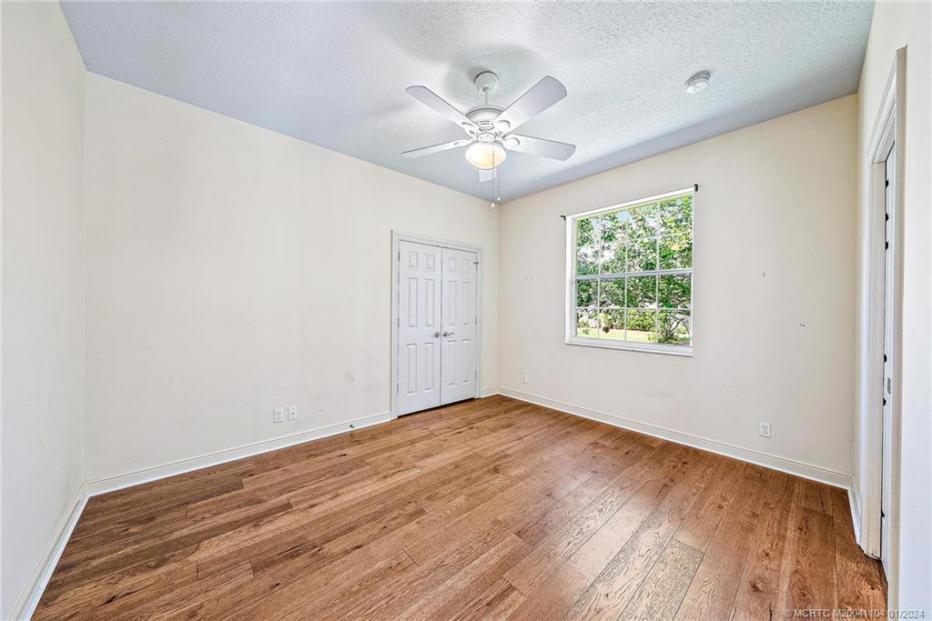 105 Henry Sewall Way Stuart, FL 34996 - Photo 22 of 33 an empty room with wooden floor chandelier fan and windows