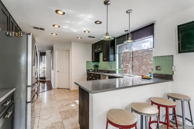 a kitchen with stainless steel appliances granite countertop a sink a stove and a refrigerator