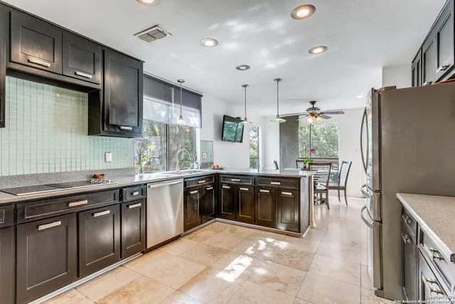 a large kitchen with stainless steel appliances granite countertop a sink stove and refrigerator