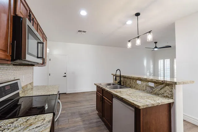 a kitchen with stainless steel appliances granite countertop a sink a stove and a wooden floors