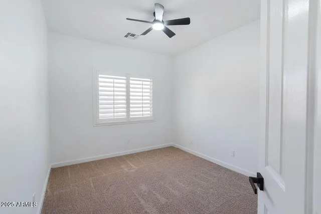 an empty room with windows and fan