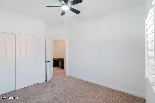an empty room with a window and a chandelier fan