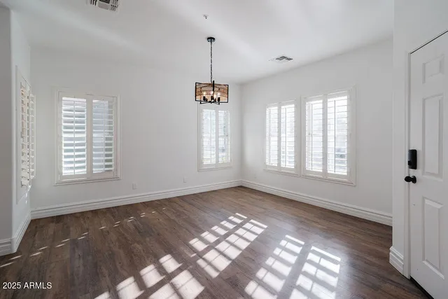 a view of an empty room with window and wooden floor