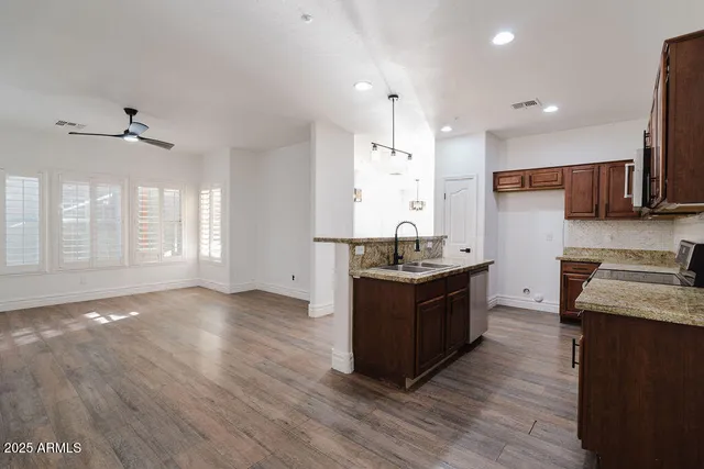a kitchen with stainless steel appliances granite countertop a sink a stove and a wooden floors