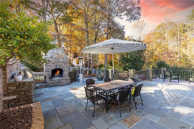 a view of a patio with a dining table and chairs under an umbrella with a fire pit