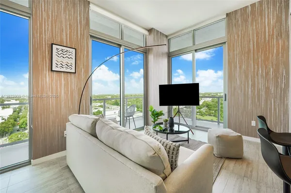 a living room with furniture a flat screen tv and a large window