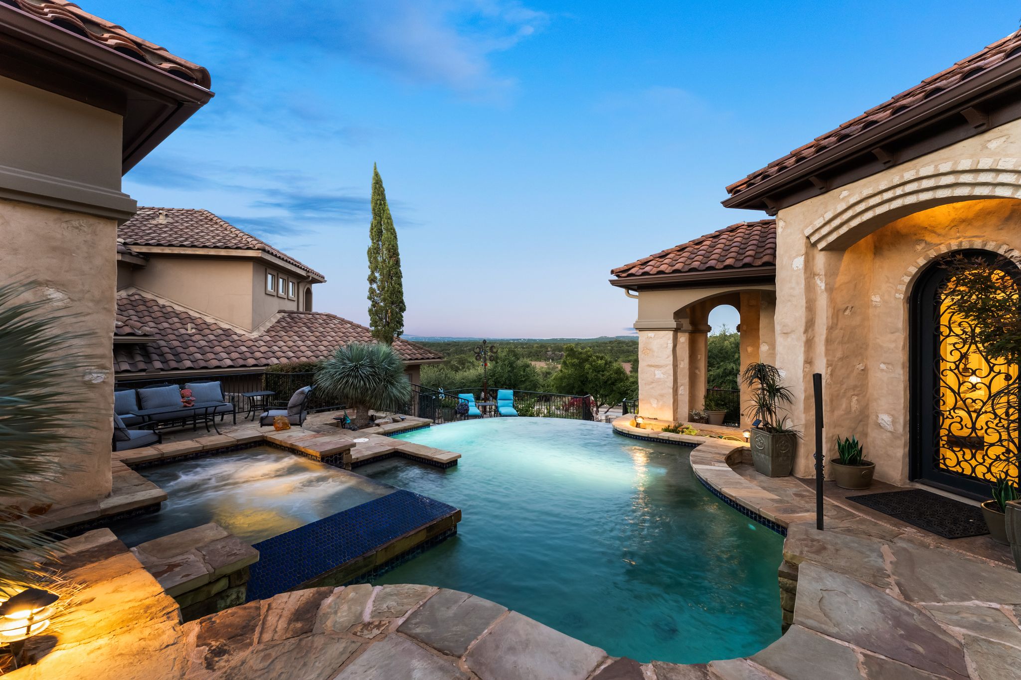 Resort style pool and hot tub at dusk