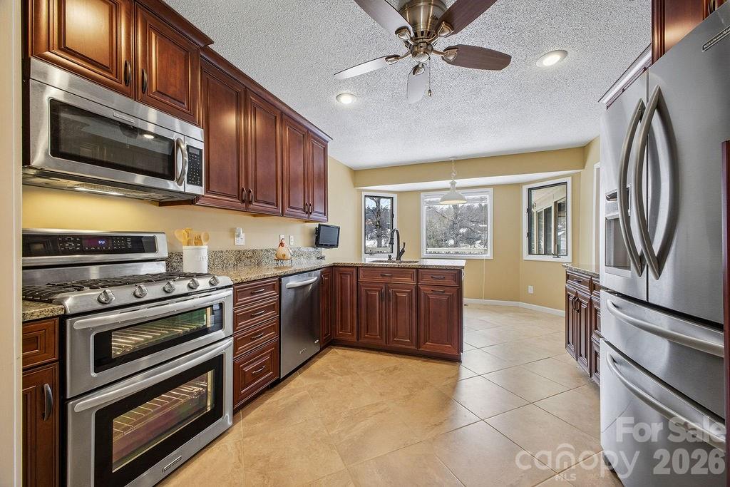 3100 Cove Loop Road Hendersonville, NC 28739 - Photo 13 of 43 a kitchen with stainless steel appliances granite countertop a stove top oven a sink dishwasher a refrigerator and cabinets with wooden floor
