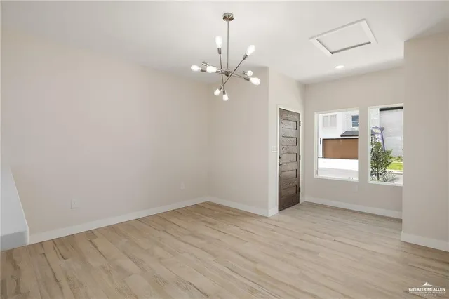 an empty room with wooden floor chandelier fan and windows