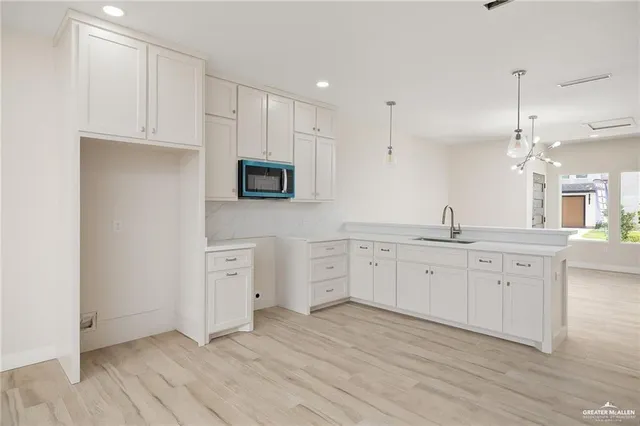 a large kitchen with cabinets stainless steel appliances a sink and wooden floor