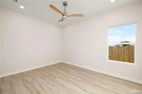 an empty room with a window and ceiling fan