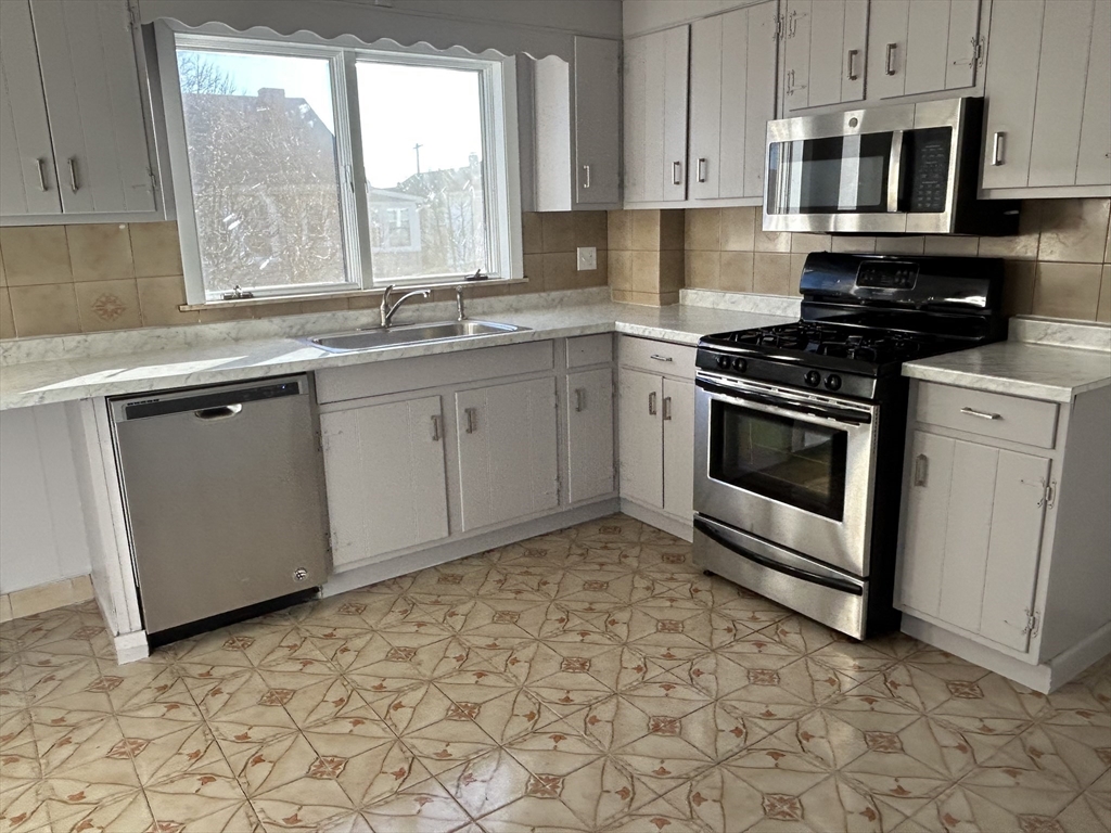 a kitchen with stainless steel appliances granite countertop a stove a sink and a microwave