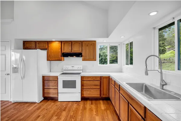 a kitchen with stainless steel appliances wooden floor sink and wooden cabinets
