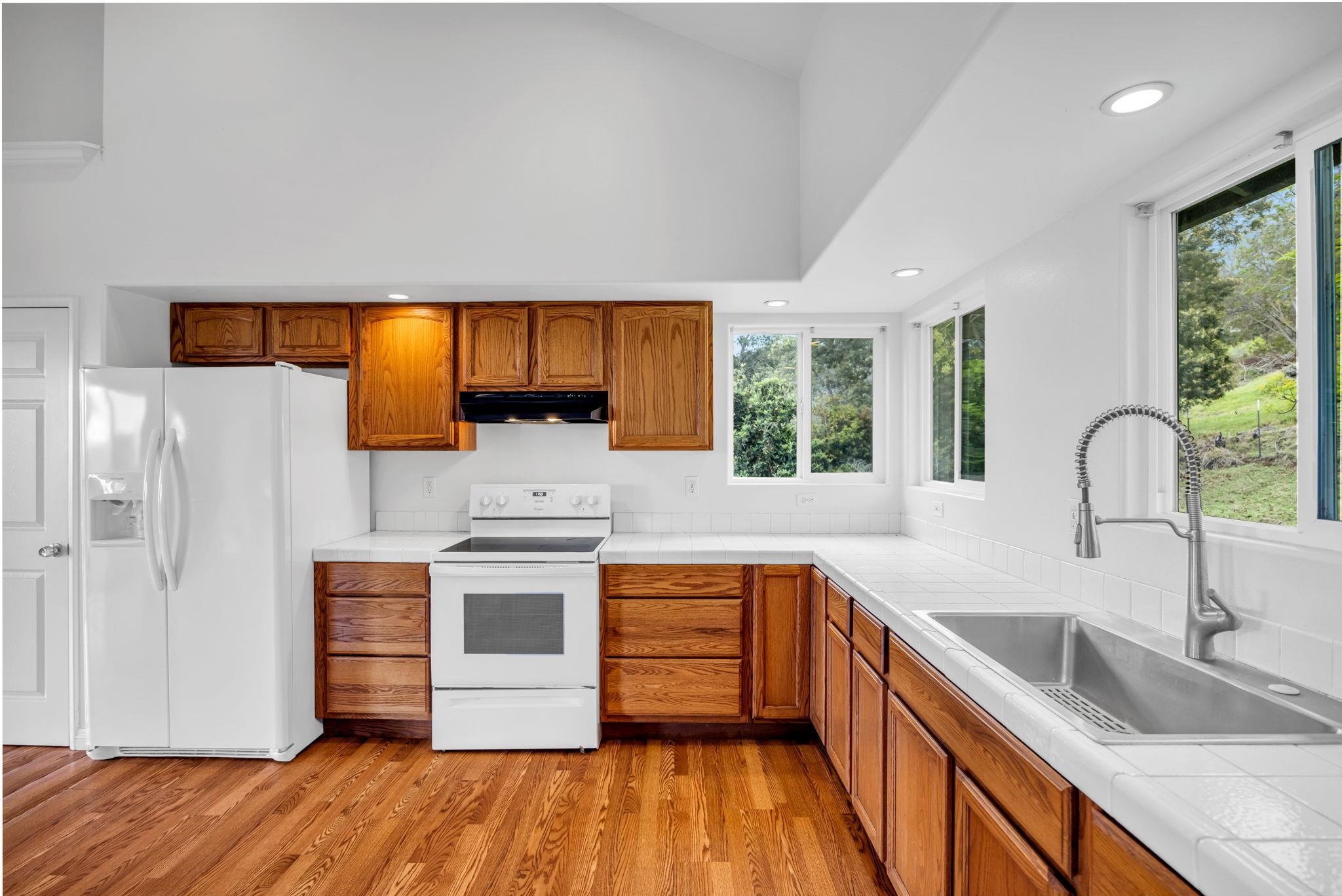 115 Alae Road Kula, HI 96790 - Photo 12 of 50 a kitchen with stainless steel appliances wooden floor sink and wooden cabinets