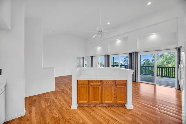 a kitchen with stainless steel appliances granite countertop a sink a stove a refrigerator a microwave oven with wooden cabinets and floor