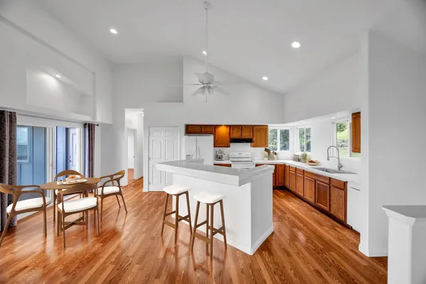 a kitchen with stainless steel appliances granite countertop a stove top oven a sink a dining table and chairs with wooden floor