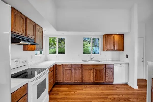 a kitchen with stainless steel appliances granite countertop a sink a stove a refrigerator a microwave oven with wooden cabinets and floor