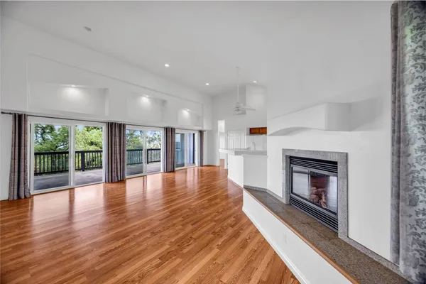 a view of an empty room with wooden floor fireplace and a window
