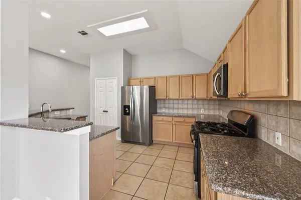 a kitchen with stainless steel appliances granite countertop a sink and a refrigerator