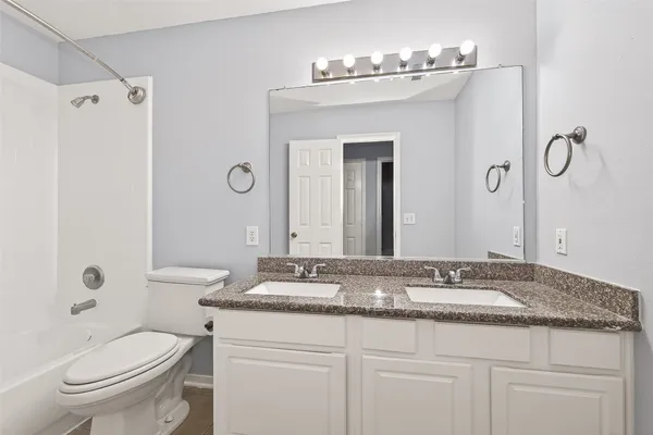 a bathroom with a granite countertop sink a toilet and a mirror