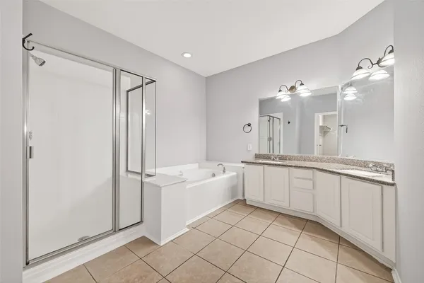 a large white bathroom with a double vanity sink a mirror and a bathtub