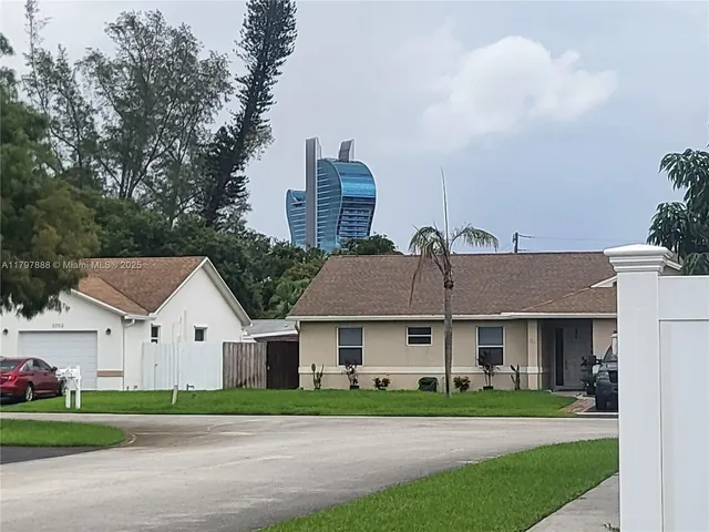 a view of house with a big yard and large trees