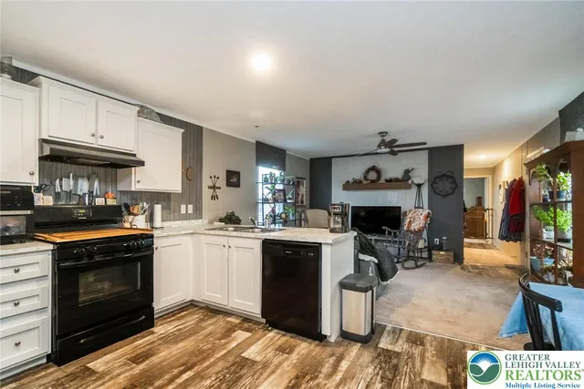 a kitchen with granite countertop a stove top oven a sink dishwasher and a fireplace with wooden floor